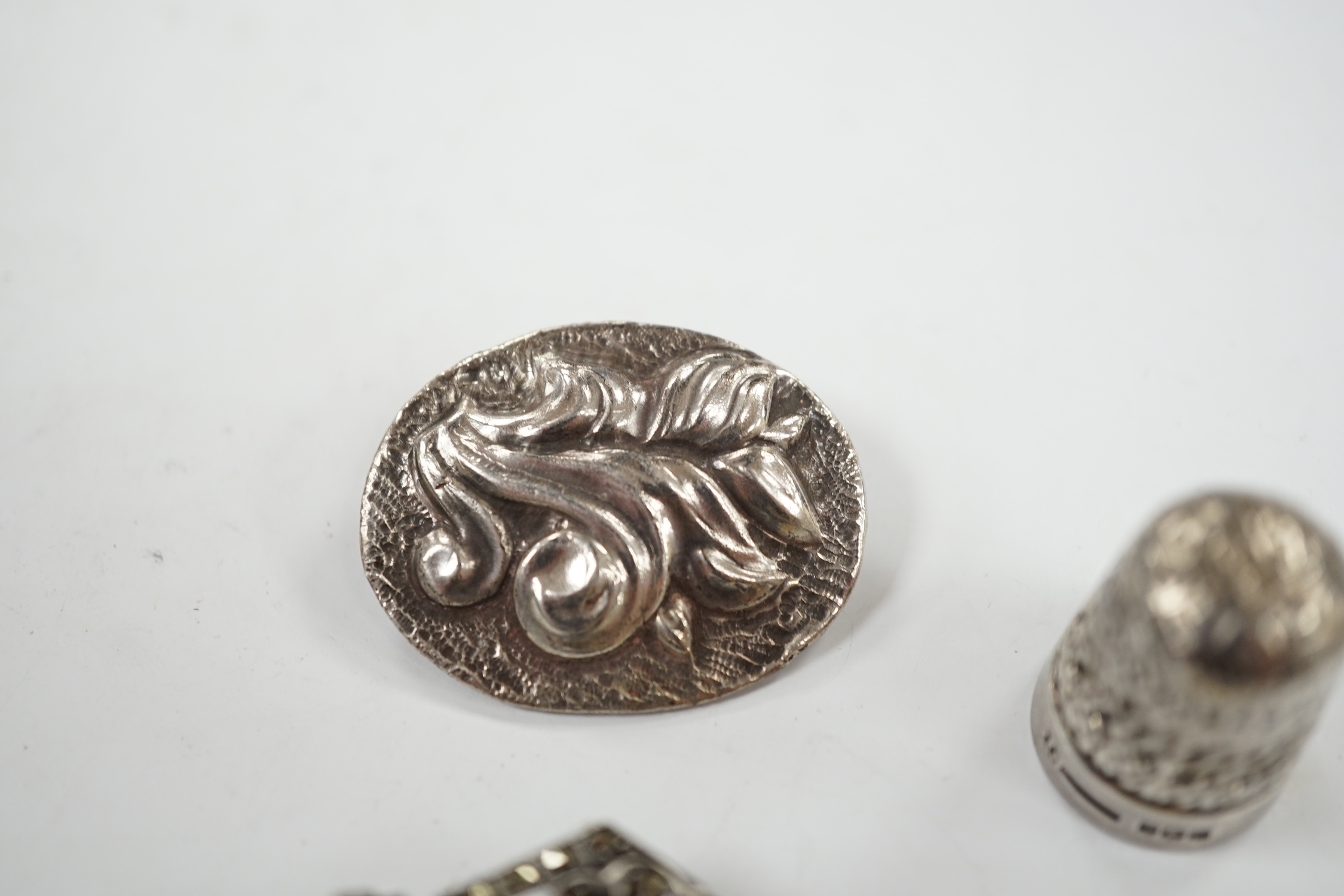 A George V silver thimble, a later silver brooch, a white metal, marcasite and black onyx brooch and one other brooch.
